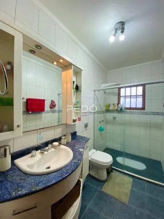 Um banheiro com revestimento cerâmico e box de vidro.