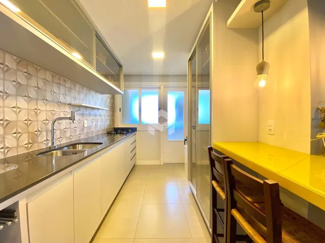 Vista interna de uma cozinha moderna com armários brancos e revestimento de parede.