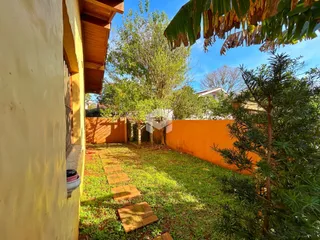 Vista externa da casa com jardim e muro de cor laranja.