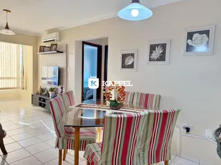 Uma sala de jantar com mesa de vidro e cadeiras listradas em um ambiente claro.