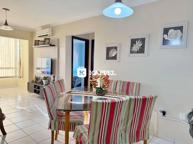 Uma sala de jantar com mesa de vidro e cadeiras listradas em um ambiente claro.