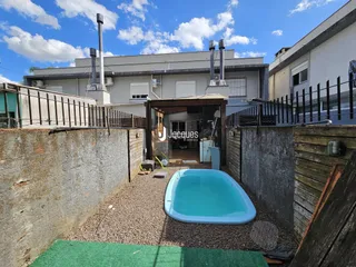 Vista externa de uma propriedade com piscina e muro.