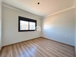 Imagem de uma sala com piso de madeira clara e paredes brancas.