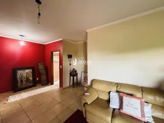 Sala de estar com paredes vermelhas e sofá bege em um imóvel no Brasil.