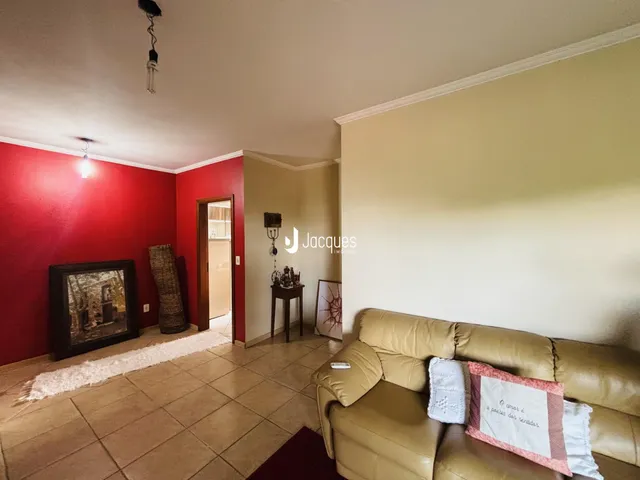 Sala de estar com paredes vermelhas e sofá bege em um imóvel no Brasil.