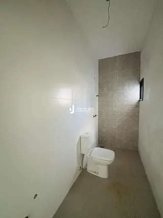 Corredor interno com acesso a um banheiro com azulejos.