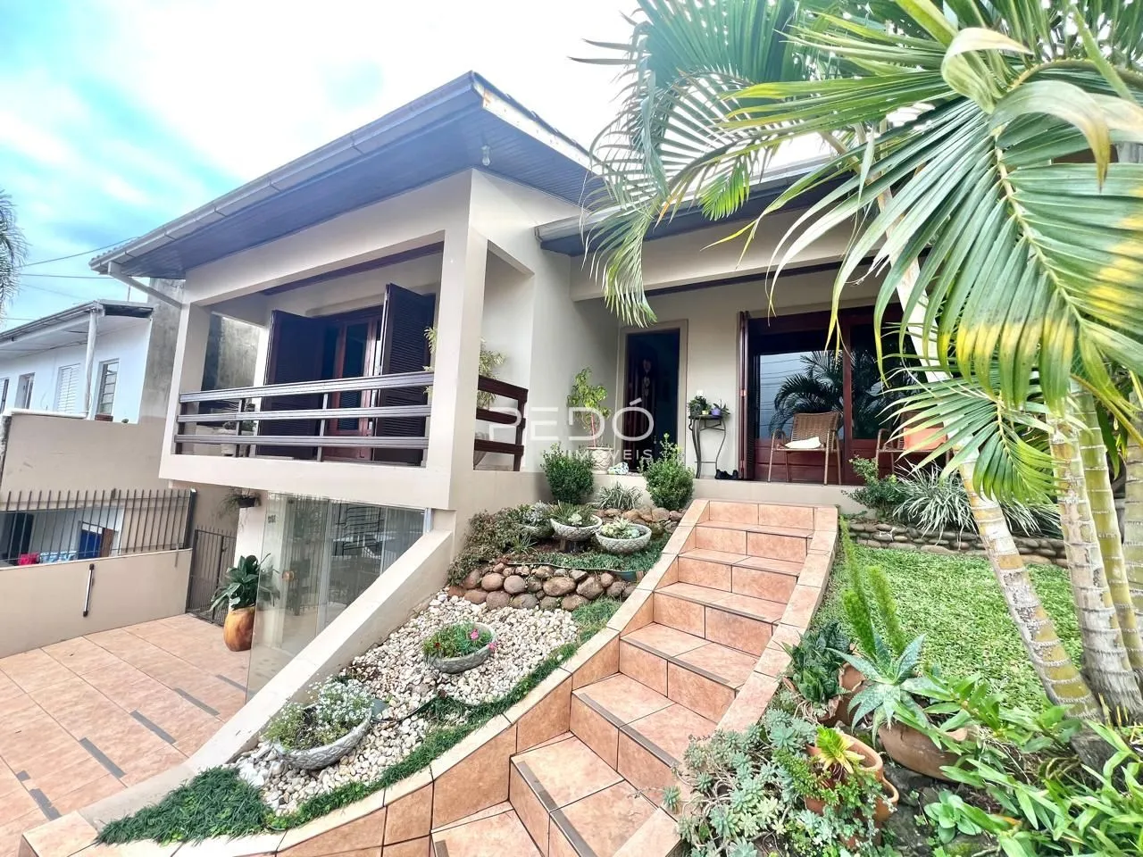 Fachada de uma casa em Lajeado, Brasil com jardim e escadaria externa.