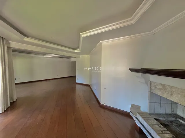Ambiente interno de uma sala longa com piso de madeira e detalhes arquitetônicos.