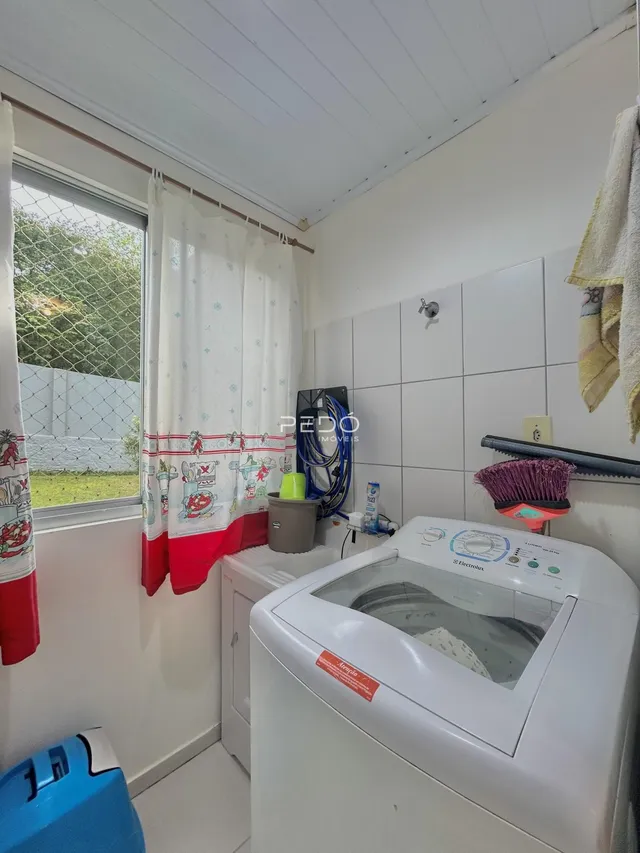 Foto de um ambiente interno com máquina de lavar roupa e paredes brancas.