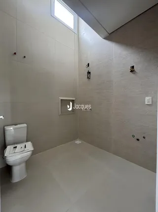 Banheiro com piso de cerâmica e paredes revestidas em tons neutros.