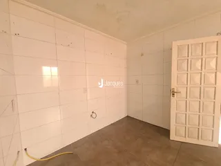 Interior de um ambiente com paredes brancas e piso de cerâmica.