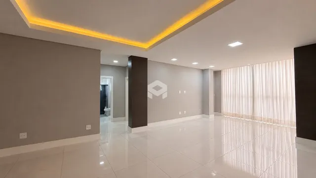 Uma área interna ampla com piso de cerâmica clara e iluminação moderna.