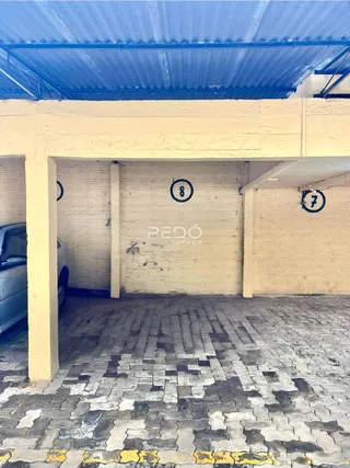 Vista da fachada de uma estrutura externa com piso de paralelepípedos.