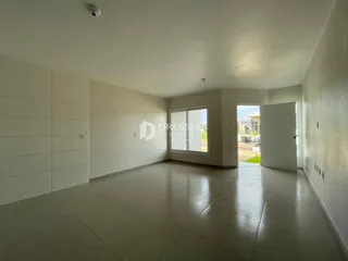 Ambiente interno de uma sala ampla com piso de cerâmica e paredes brancas.