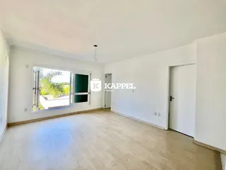 Sala ampla com piso de madeira e grande janela voltada para o exterior.