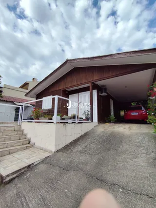 Fachada externa de uma residência com escadaria e área pavimentada.