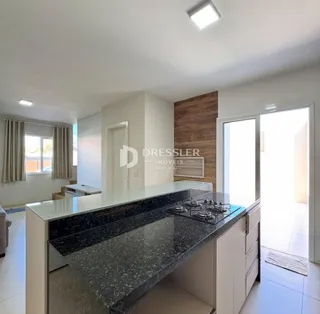Vista da cozinha com bancada de granito e armários brancos.