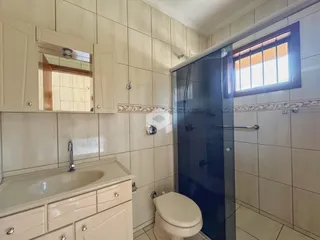 Um banheiro com revestimento cerâmico e box de vidro transparente.