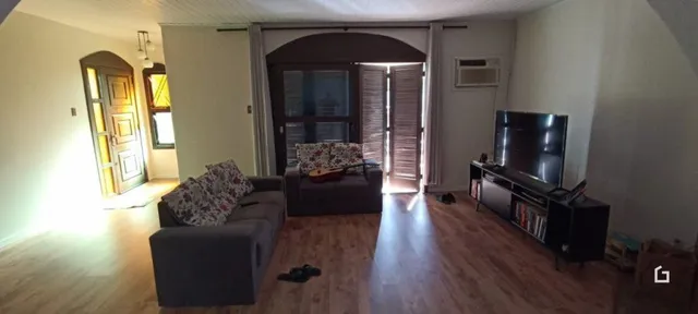 Sala de estar com piso de madeira e porta de entrada.