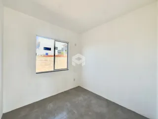 Interior de uma sala com paredes brancas e piso de concreto.