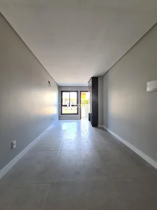 Corredor longo com piso claro e portas de saída para o exterior.