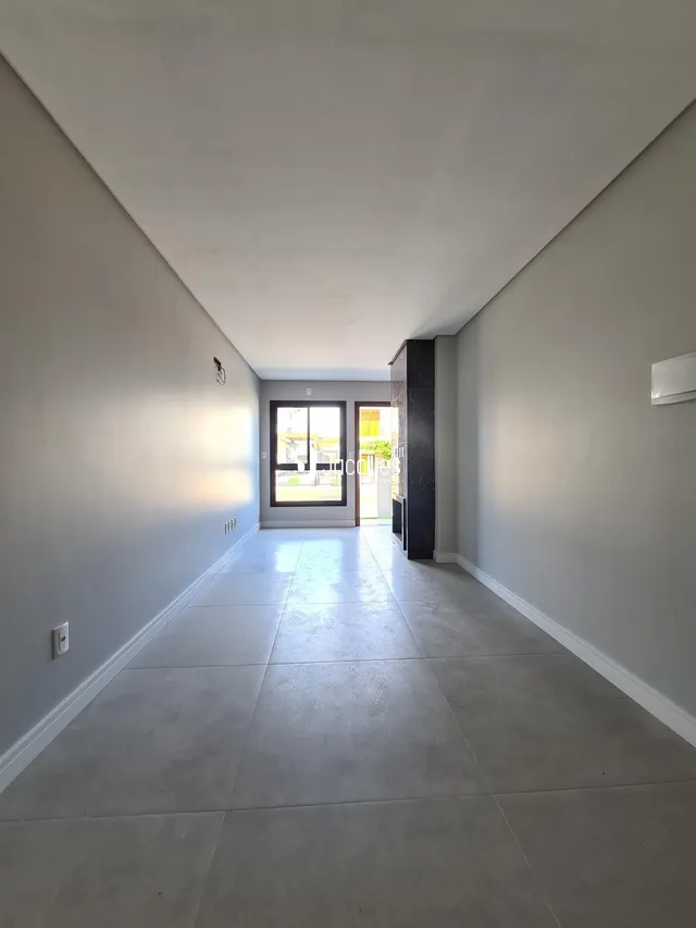 Corredor longo com piso claro e portas de saída para o exterior.