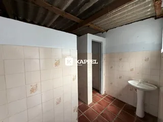 Foto interna de um banheiro com azulejos brancos e piso de terracota.