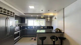 Vista da cozinha moderna com armários escuros e bancada de ilha.