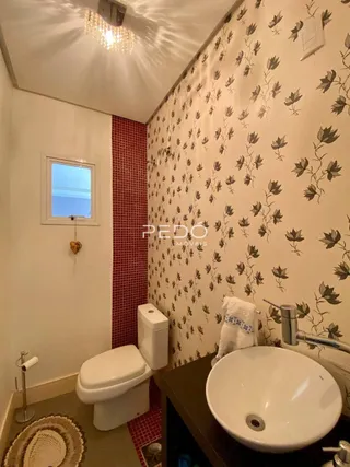 Foto de um banheiro com azulejos vermelhos e papel de parede estampado.