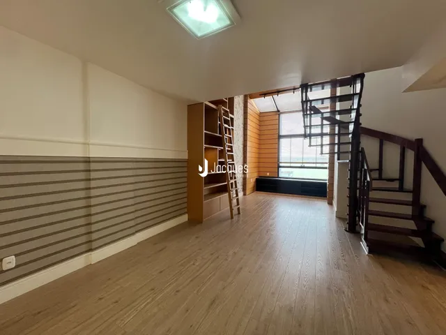 Ambiente interno de uma sala com piso de madeira e escadaria.