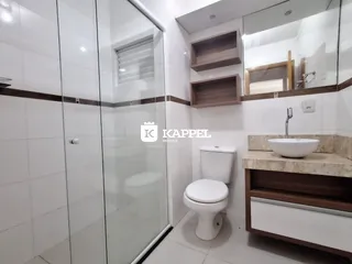 Banheiro com box de vidro e bancada de mármore clara.