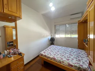 Quarto com armários de madeira e cama em um imóvel no Brasil.
