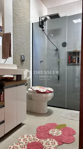 Foto de um banheiro com revestimento cerâmico e box de vidro.