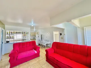 Sala de estar com sofás vermelhos e piso de cerâmica em um imóvel no Brasil.