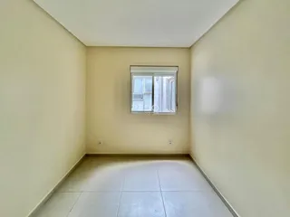 Vista interna de um corredor com paredes claras e piso de cerâmica.