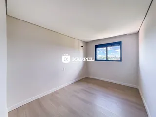 Foto de um cômodo interno com piso de madeira e uma janela mostrando a paisagem.