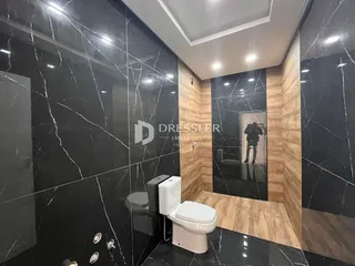 Banheiro com revestimento de mármore preto e branco.