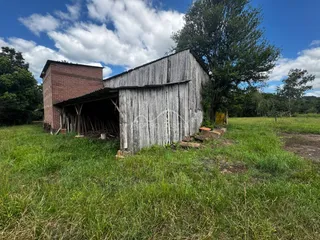 Fachada de um celeiro antigo de madeira e tijolo em uma área de campo.