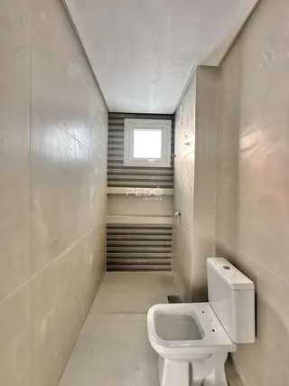 Corredor estreito com revestimento de cerâmica e vaso sanitário em um imóvel.