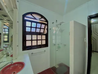 Foto de um interior de banheiro com janela decorativa e box de vidro.