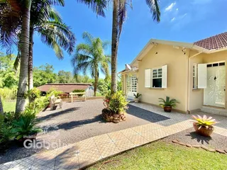 Fachada de uma casa em Lajeado, Brasil, com jardim e palmeiras.