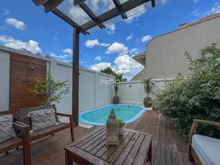 A área externa da propriedade exibe uma piscina e um deck de madeira.