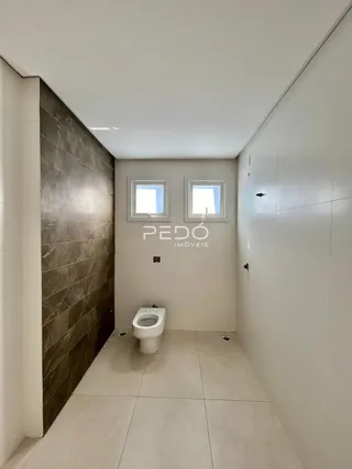 Corredor interno com piso de cerâmica e vaso sanitário em um imóvel.