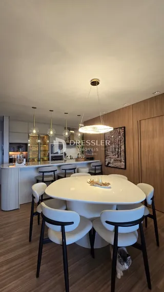 Uma mesa de jantar branca com cadeiras modernas em um ambiente interno.