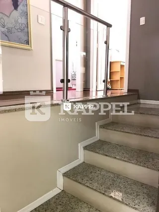 Uma foto de uma escadaria com guarda-corpo de vidro em um imóvel.