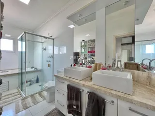 Foto de um banheiro moderno com box de vidro e bancadas brancas.