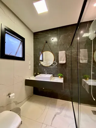 Banheiro moderno com revestimento em mármore branco e box de vidro.