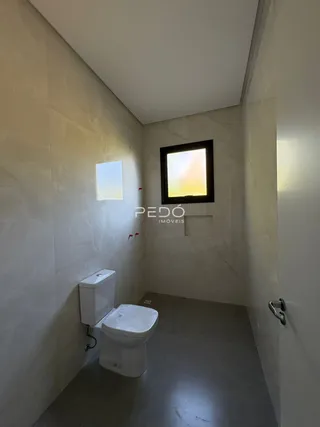 Vista de um corredor interno com um vaso sanitário branco.