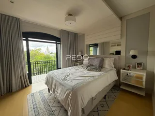 Quarto com vista para a paisagem externa através de grandes janelas.