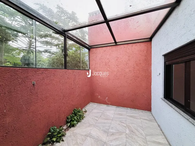 Vista de uma área externa com parede vermelha e piso de cerâmica.